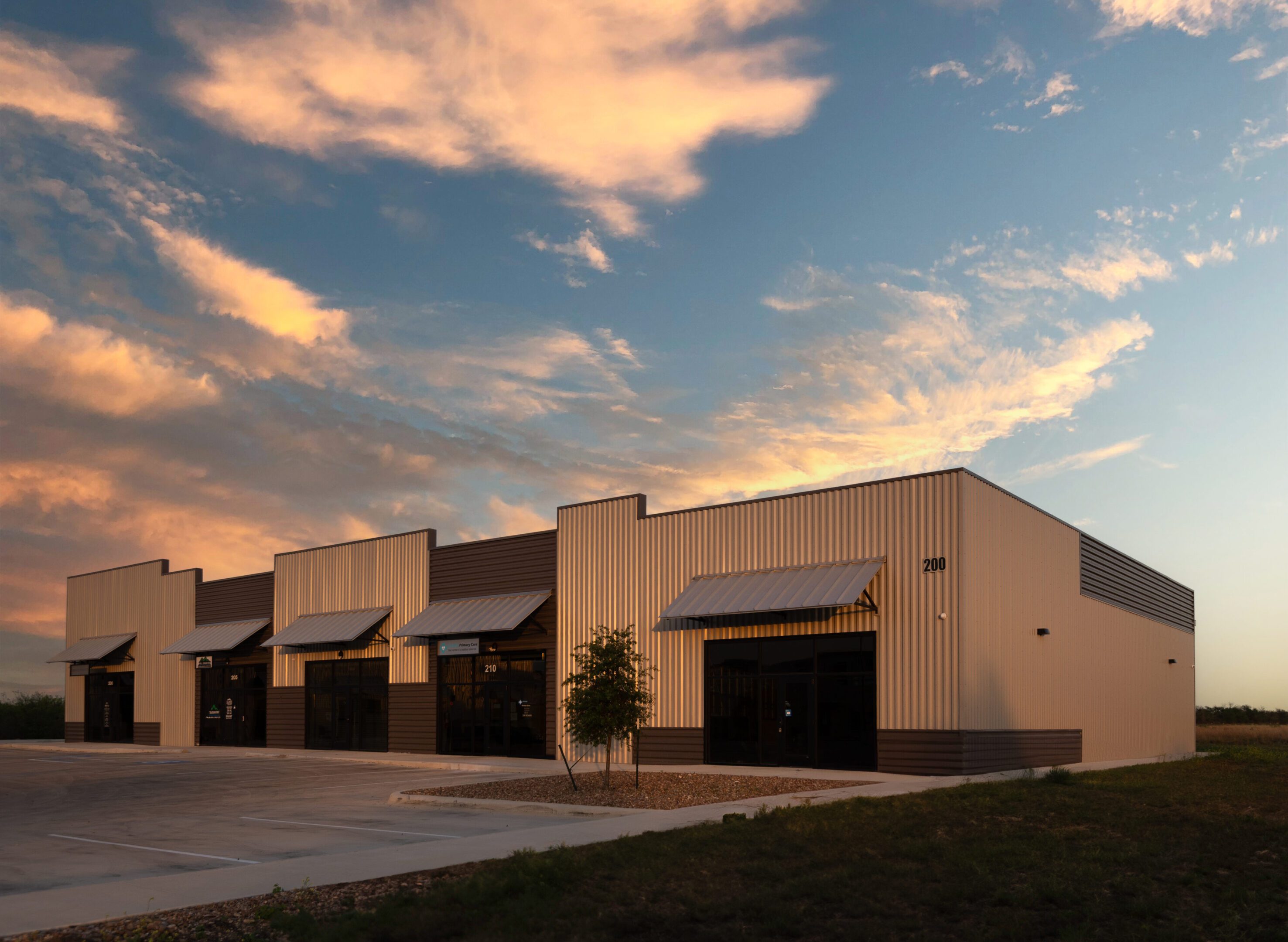 C19A6556_nobanner A large warehouse with several storefronts and a parking lot.